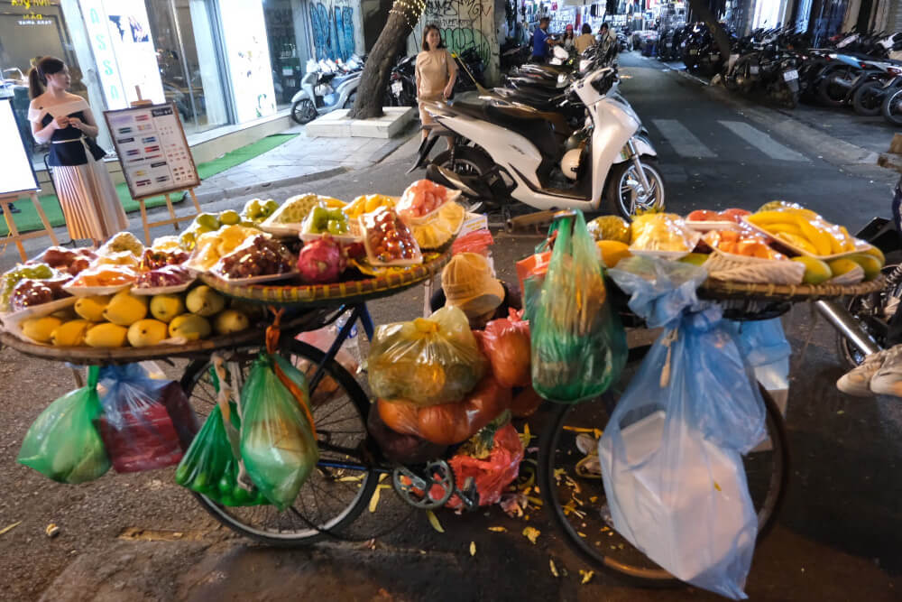 A bicycle carrying many fruits for sale.